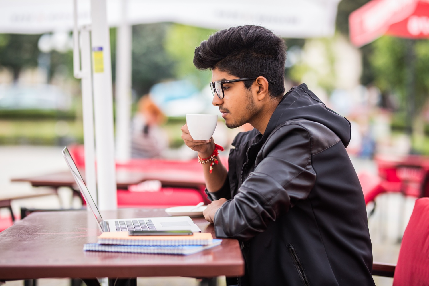 Blog 9 indian man using laptop while drinking cup coffee outdoor street cafe 1